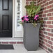 A Mayne graphite gray rectangular planter with pink flowers in it.