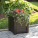 An espresso Mayne Lakeland planter with flowers growing in it on an outdoor patio table.
