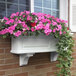 A white Mayne Nantucket window box with pink flowers.