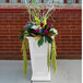 A white Mayne Fairfield planter with colorful flowers and branches.