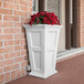 A white rectangular Mayne Fairfield planter with red flowers in it.