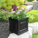 A black square Mayne Nantucket planter with pink flowers in it.