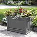 A Mayne graphite gray trough planter with flowers in it.