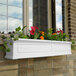 A white rectangular Mayne window box with flowers in it.