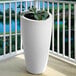 A white Mayne Modesto planter with a plant in it on a balcony.