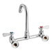 A silver Regency wall mount faucet with knobs and a swivel gooseneck spout.
