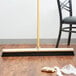 A Carlisle black bristle broom head on a wooden floor.
