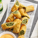 A plate of The Gourmet Egg Roll Co. spinach and cheese egg rolls with dipping sauce.