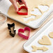 A person using the Wilton heart shaped cookie cutter to cut out cookies.