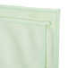 A close up of a green microfiber cloth with white stitching.