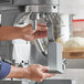 A person using an Avantco bowl scraper attachment on a mixer to make bread.