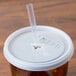 A plastic straw in a white Cambro lid on a plastic cup.