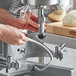 A person using the Avantco dough hook attachment on a machine to make dough.