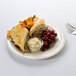 A Thunder Group ivory melamine plate with a sandwich, coleslaw, and grapes on it.