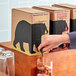A person pouring Wandering Bear Organic Caramel Cold Brew Coffee from a box into a glass.