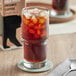 A glass of Wandering Bear Organic Straight Black Cold Brew Coffee with ice on a table with a spoon on a napkin.