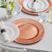 A table set with Choice rose gold charger plates and glasses.