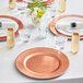 A table set with copper Choice beaded charger plates and glasses with flowers.