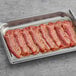 A tray of Swift Fully Cooked Thin Bacon slices on a gray surface.