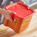 A woman holding a red Cambro CamSquares polypropylene container.