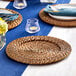 A table set with Acopa rattan charger plates, blue and white plates, and candles.