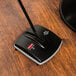 A black and grey Rubbermaid Executive Series floor sweeper on a wood surface.