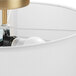 A white linen Globe flush mount light with a matte brass base and a light bulb inside.
