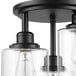A Globe matte black semi flush mount light with clear glass shades.