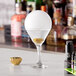 A martini glass with a white round object on the rim on a counter.