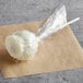 A white chocolate covered Italian cream cake pop wrapped in plastic.