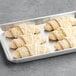 A metal tray with four Gourmand Almond Butter Croissants ready to bake.