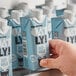 A person holding a carton of Oatly Original Oat Milk with a blue and white label.