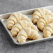 Curved butter croissants on a baking dish.