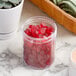 A plastic container of red candy on a counter.