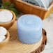 A clear jar of blue body lotion next to a jar of blue scrub on a wood surface.