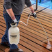 A person using a Chapin Clean 'N Seal sprayer to clean a deck.