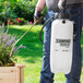 A man using a Chapin Premier Pro XP garden sprayer to water a plant.
