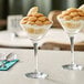 Two martini glasses of dessert with bananas and whipped cream.