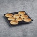 A black tray of La Rose Noire extra large puff pastry tart shells on a gray surface.