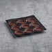 A black tray of La Rose Noire large round chocolate tart shells.