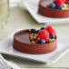 A chocolate tart with berries on a plate.