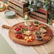An Acopa acacia wood serving board with bowls of food and a piece of cheese on it.