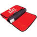 A red first aid blanket bag with a red first aid blanket with white text on it.