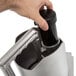 A hand pushes a black cylinder with a metal handle.