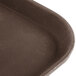 A close-up of a Carlisle brown non skid fiberglass serving tray with a dark brown bottom.