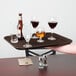 A hand holding a Carlisle brown non-skid serving tray with wine glasses and bottles on it.