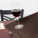 A glass of red wine on a Carlisle brown non skid fiberglass tray on a table.