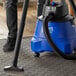 A person using a Lavex Pro wet/dry vacuum to clean a carpet.