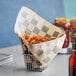 A basket of food on a table with a Choice Kraft Black Check Cone Basket Liner full of fries.