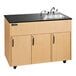 An Ozark River Manufacturing portable hot water hand sink with deep basin and black countertop on a wooden cabinet with wheels.